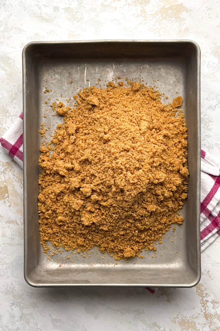 A loose mound of the unpressed crumb mixture sits in the center of a metal baking pan.