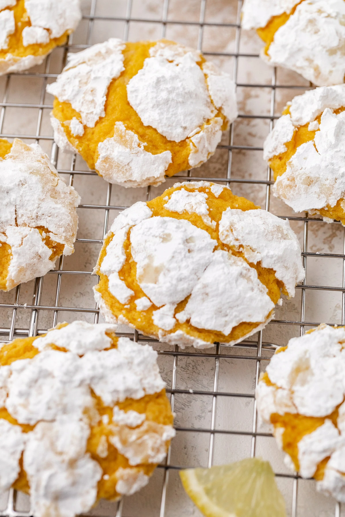 Cookie dough balls coated in powdered sugar on a rack.