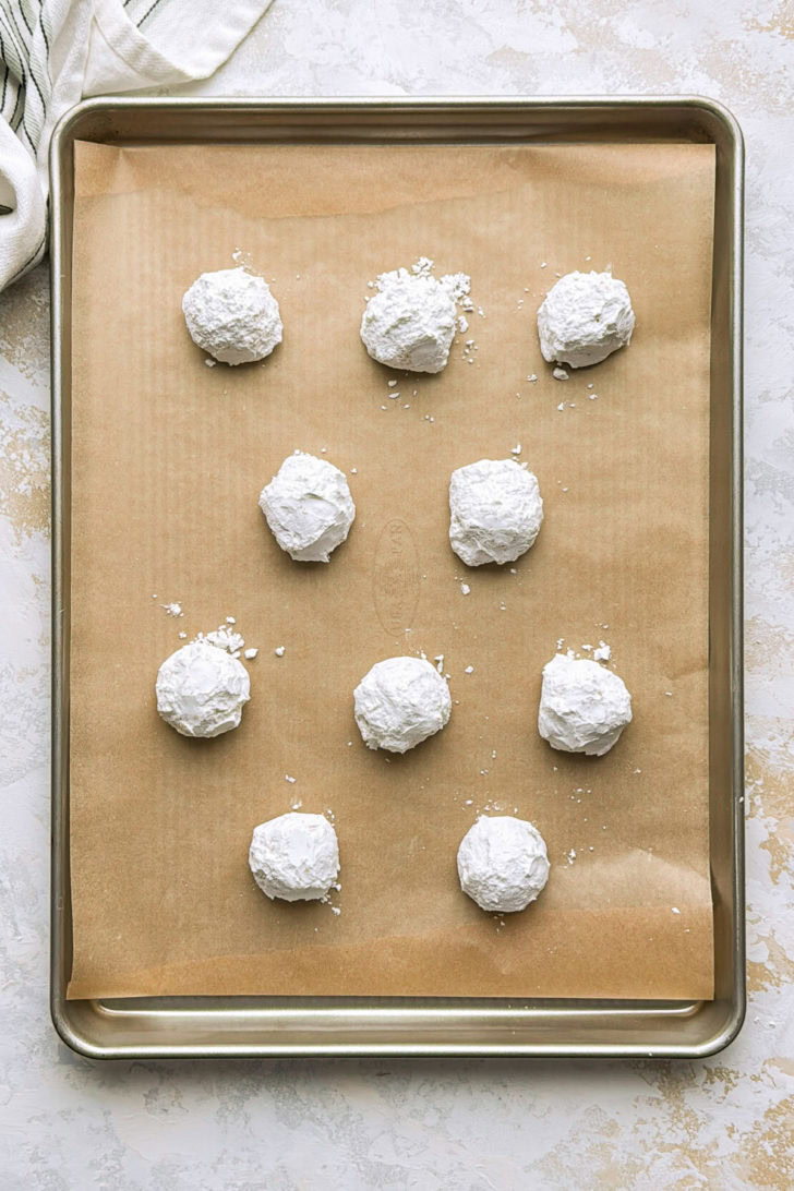 Powdered sugar topped cookies cooling on metal racks.