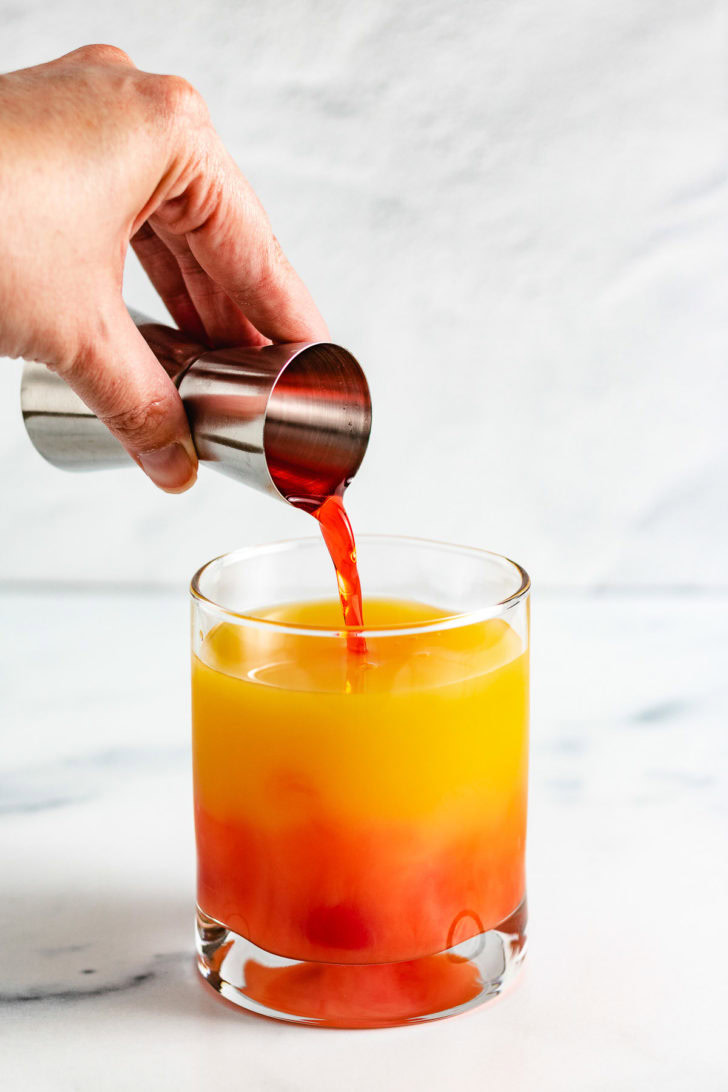 Grenadine being poured into a cocktail.