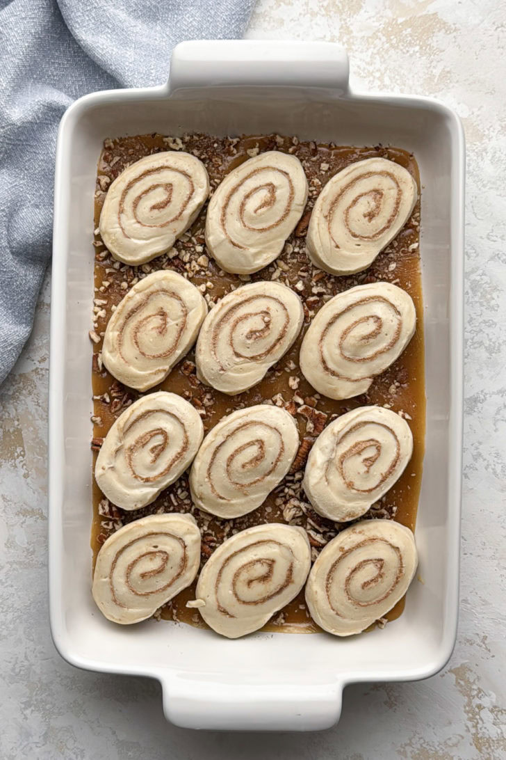 Rhodes frozen cinnamon rolls arranged over the pecan caramel topping in the baking dish before rising.
