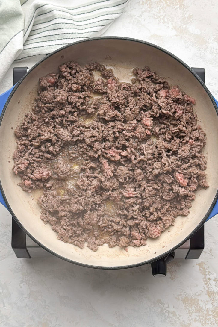 Ground beef browning in a large skillet.