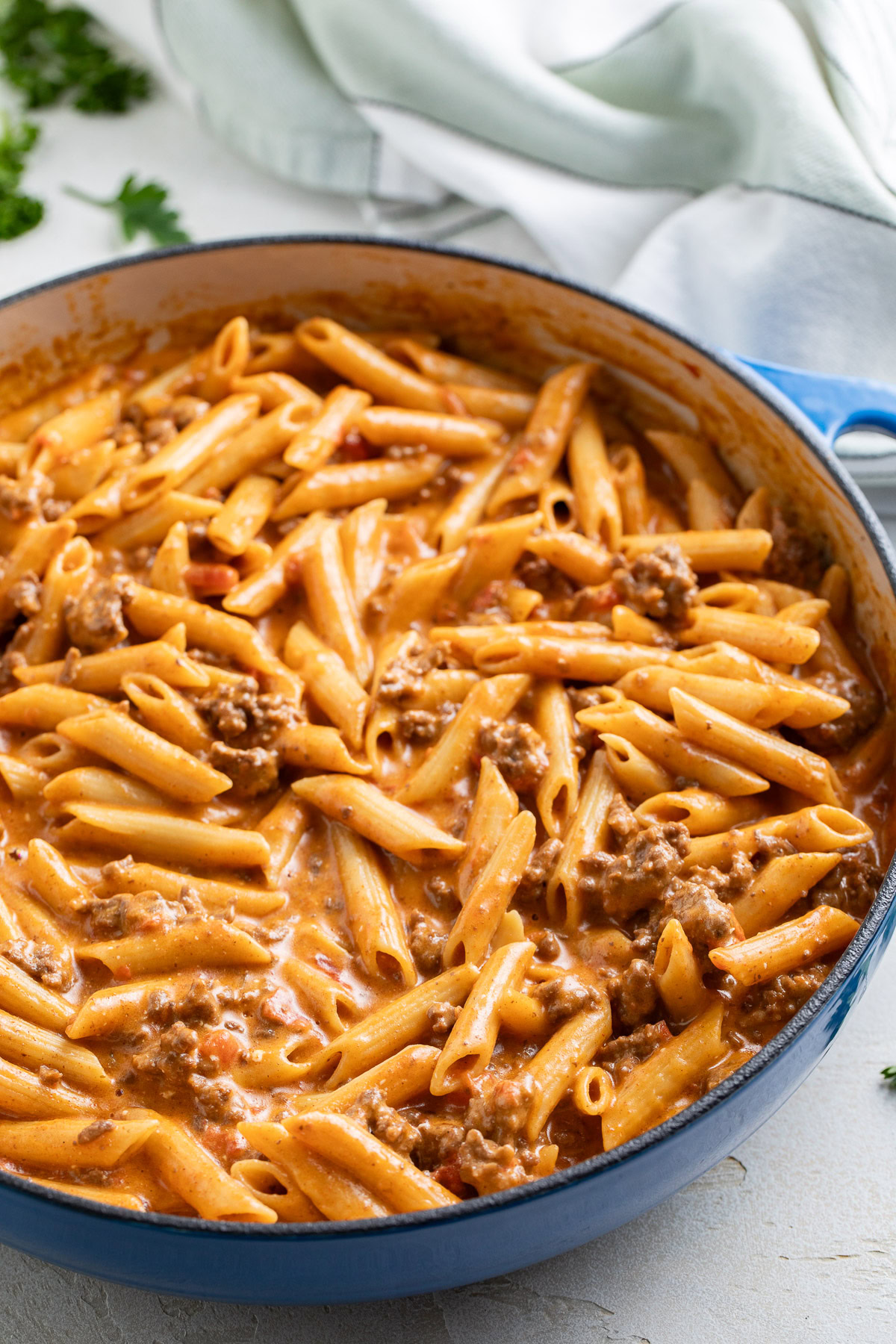 Taco penne pasta in a blue skillet on a light surface.