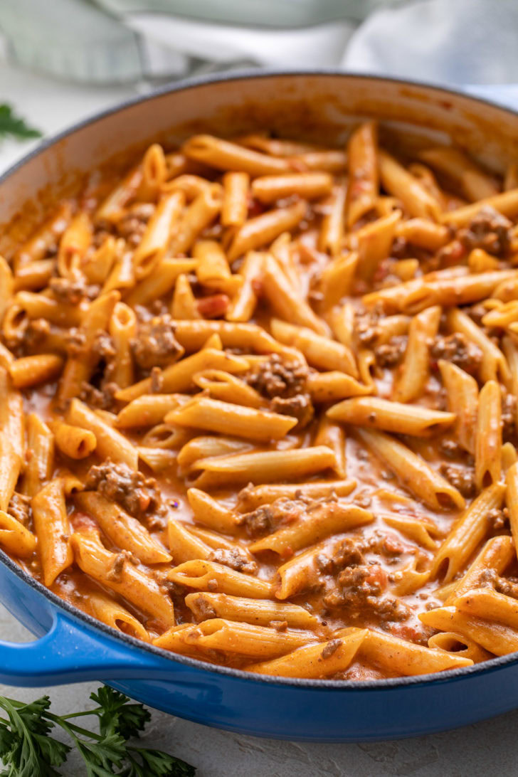 A spoonful of taco penne pasta lifted from the skillet.