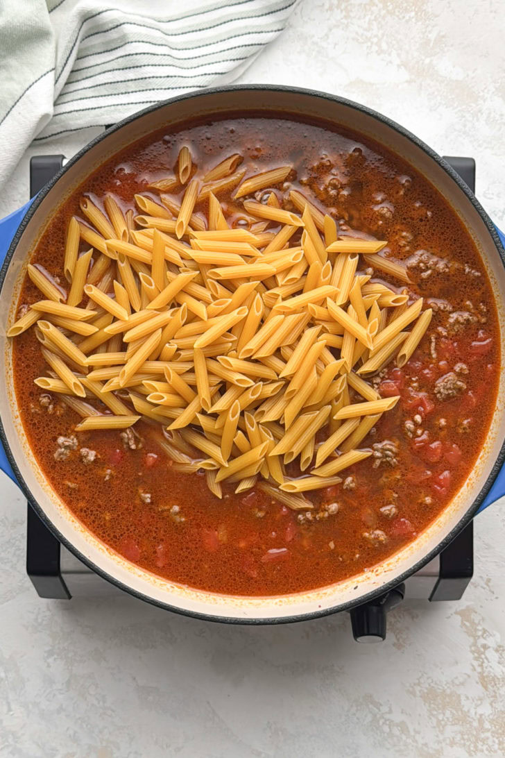 Uncooked penne added to the taco pasta mixture.