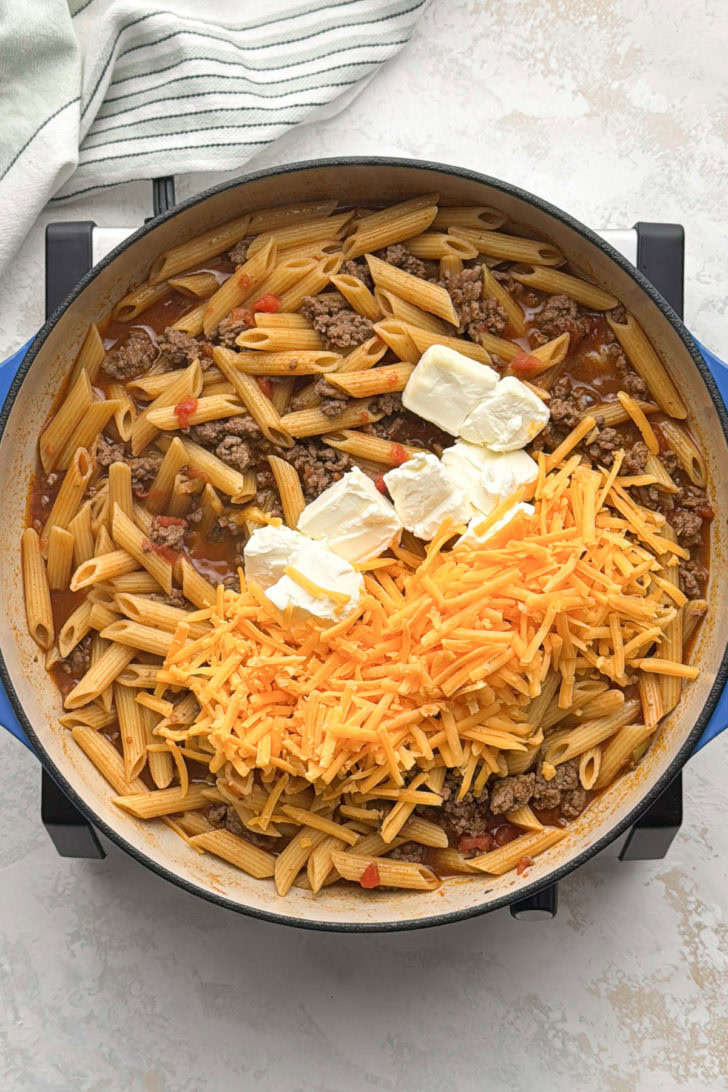 Cream cheese and shredded cheddar added to taco penne pasta.