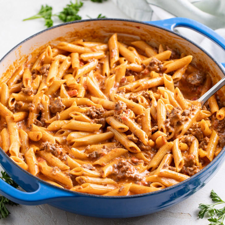 Taco penne pasta in a blue skillet with a creamy beef and cheese sauce.