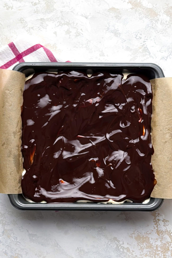 Chocolate ganache spread over cheesecake bars.