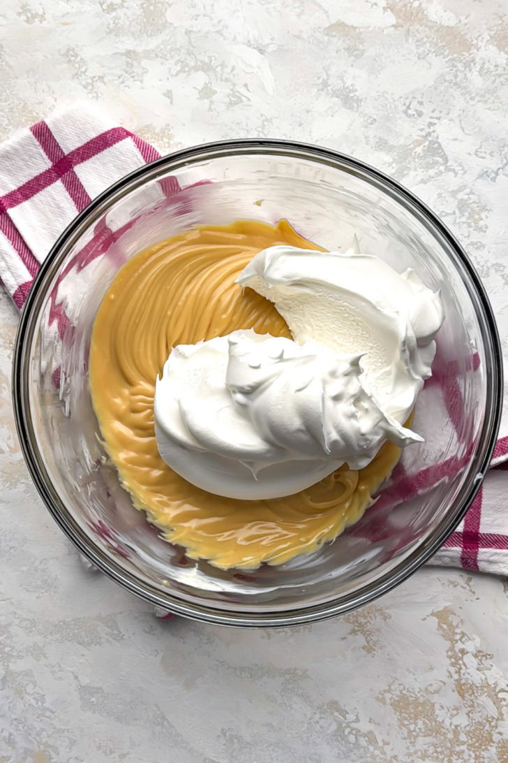 Cool whip added to a bowl of caramel filling.