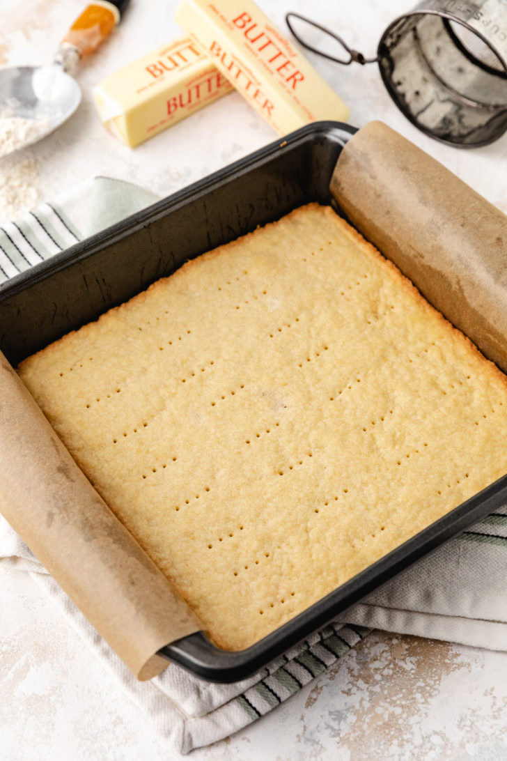 A baked dessert crust cools in a dark metal pan.