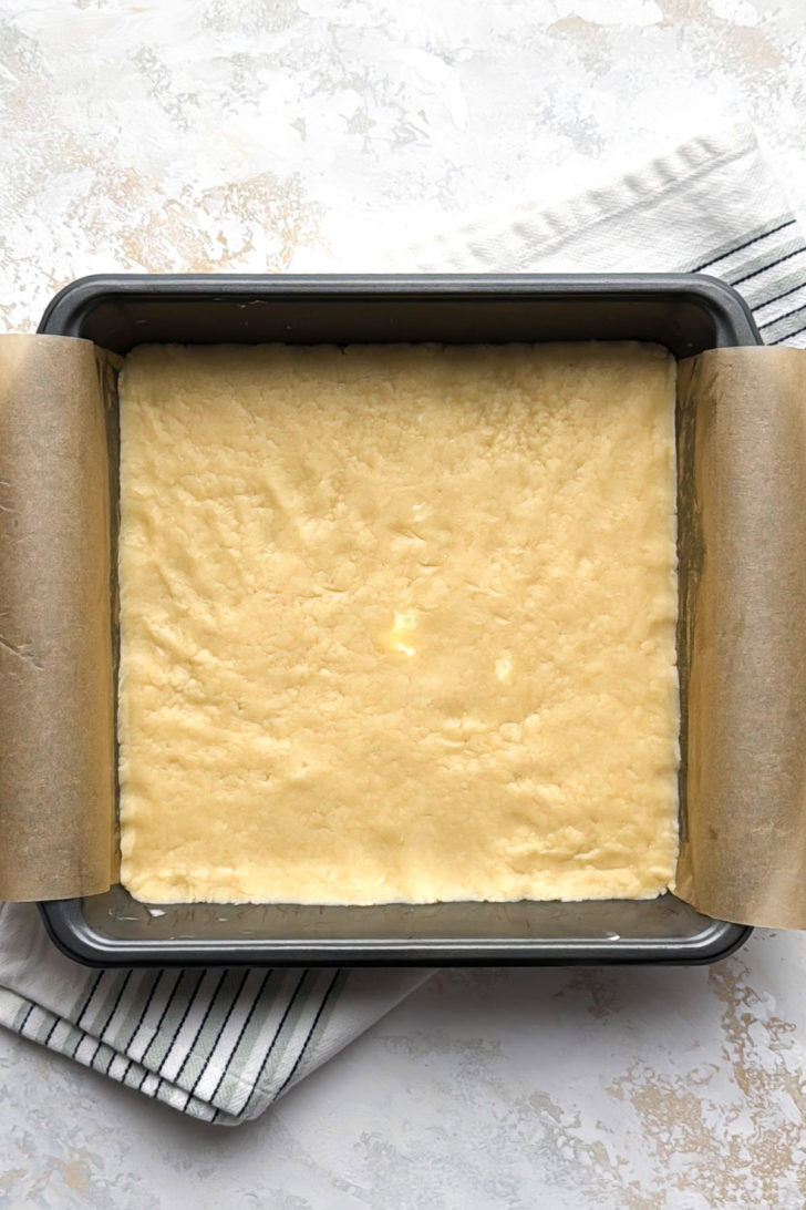 The dough is pressed into an even layer in a 9x9-inch pan.