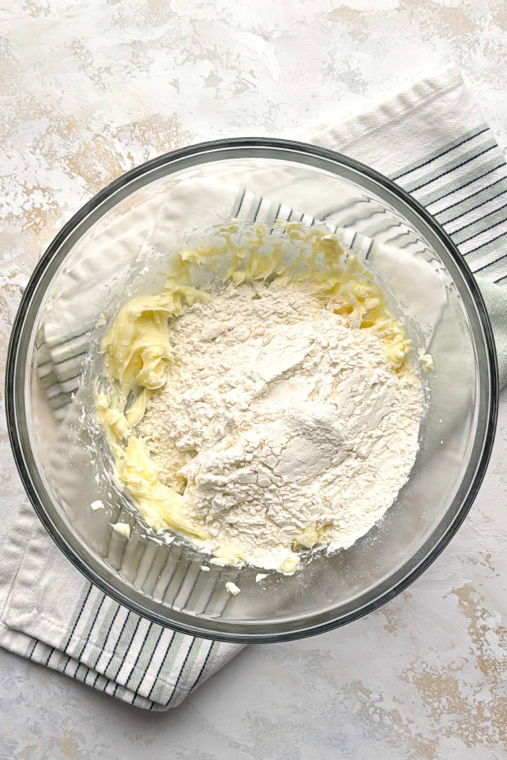 Flour is added to the butter mixture in a glass bowl for shortbread crust.