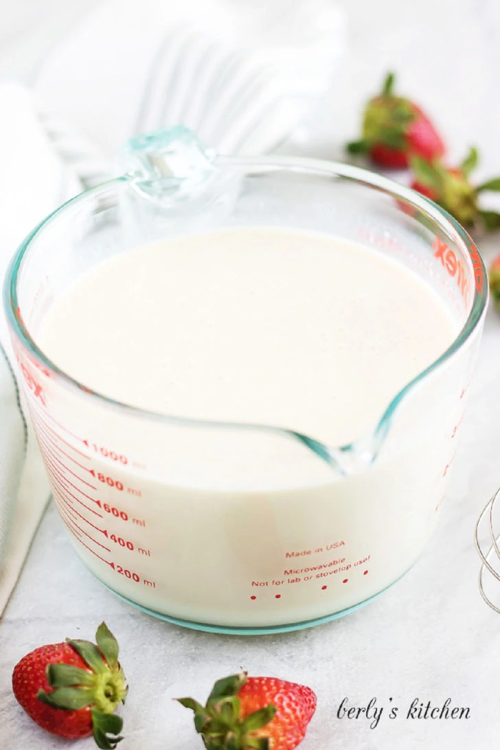 Three milks mixture in a glass measuring cup for tres leches cake.