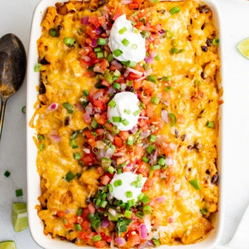 Overhead view of cheesy fiesta chicken casserole with pico de gallo and sour cream.