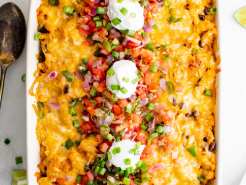 Overhead view of cheesy fiesta chicken casserole with pico de gallo and sour cream.