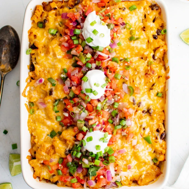 Overhead view of cheesy fiesta chicken casserole with pico de gallo and sour cream.