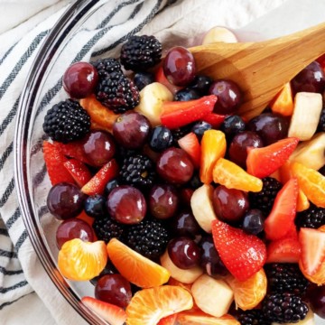Overhead view of fresh fruit salad in a glass mixing bowl.