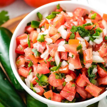 Close-up view of a white dish filled with freshly made pico de gallo.