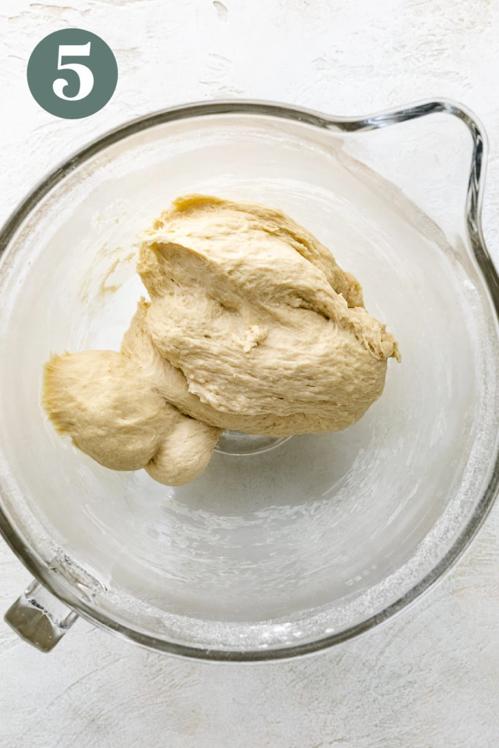 Brioche roll dough in a glass mixing bowl.