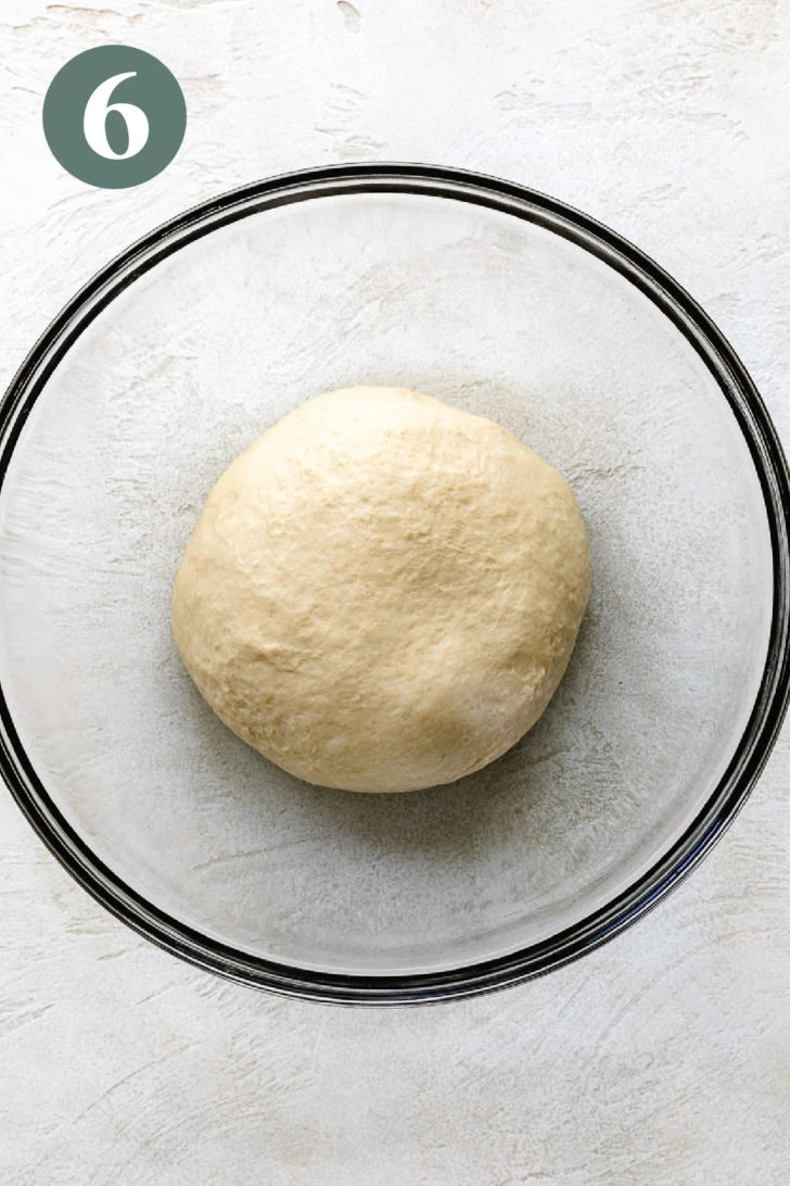 Ball of brioche dough in a glass mixing bowl.