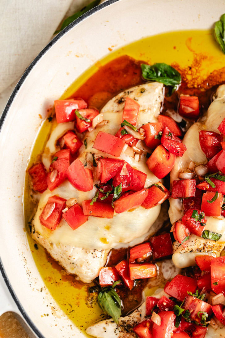 Overhead view of cheesy bruschetta chicken in a skillet.