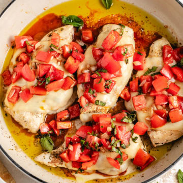 Close up view of bruschetta chicken in a tan skillet.