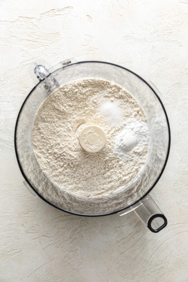Flour, baking powder, and salt in a food processor bowl before mixing.