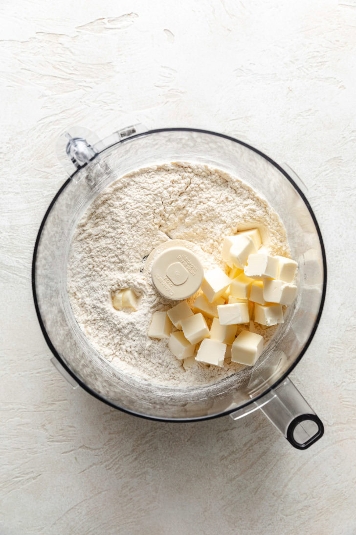 Cold cubed butter added to flour mixture in a food processor bowl.