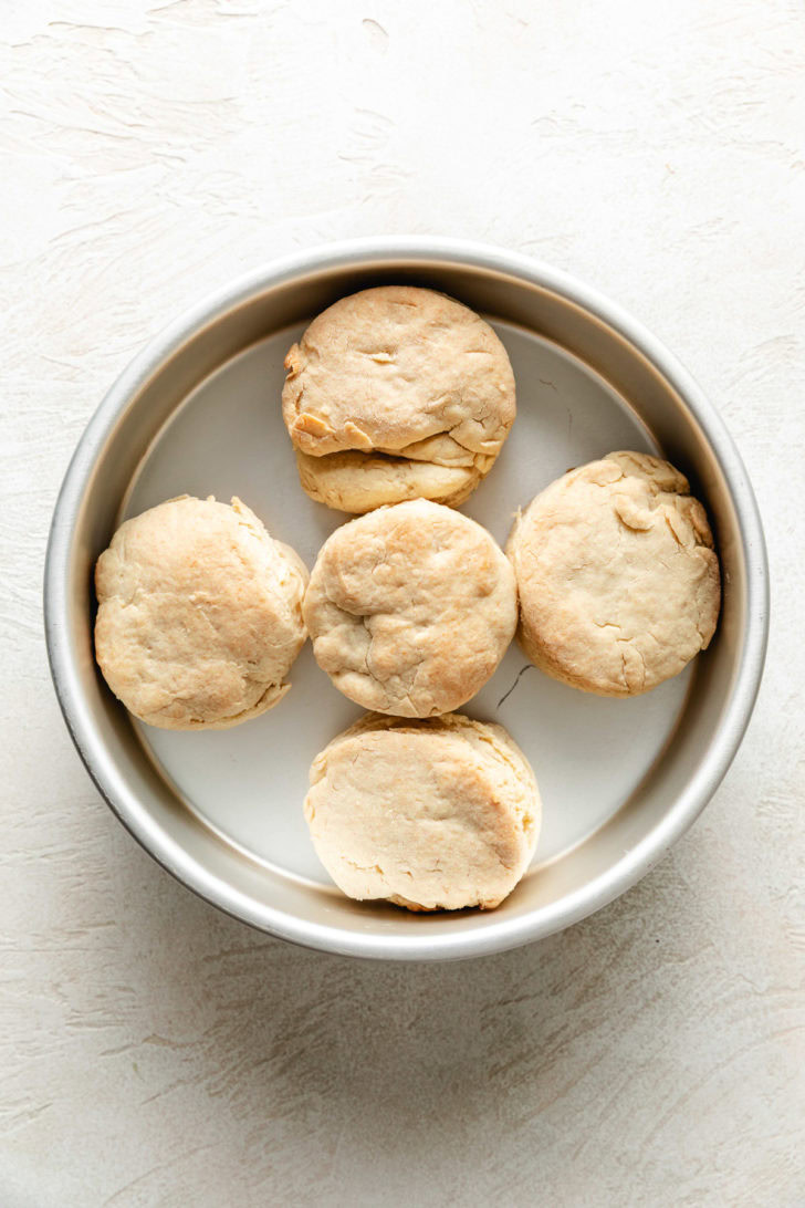 Baked golden homemade buttermilk biscuits in a round cake pan fresh from the oven.