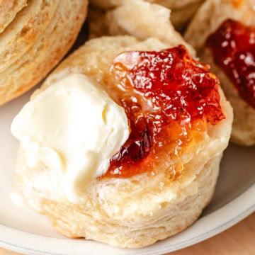 Buttermilk biscuits with jelly and butter on a plate.