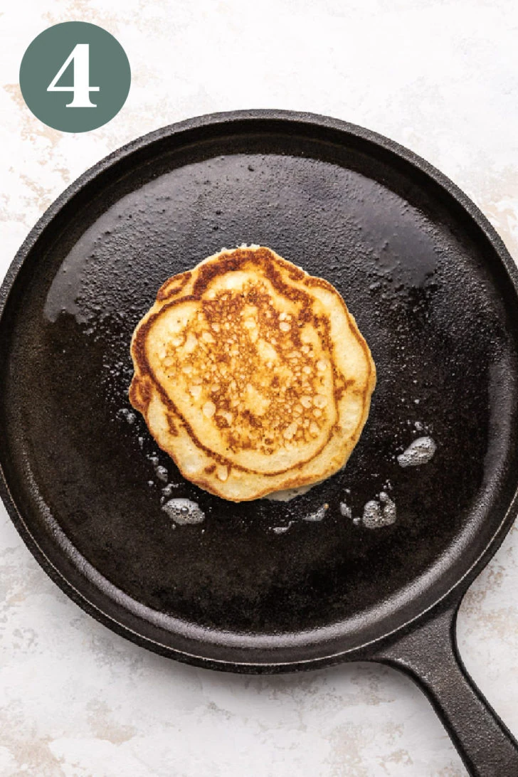 Buttermilk pancake cooking on a cast iron skillet.