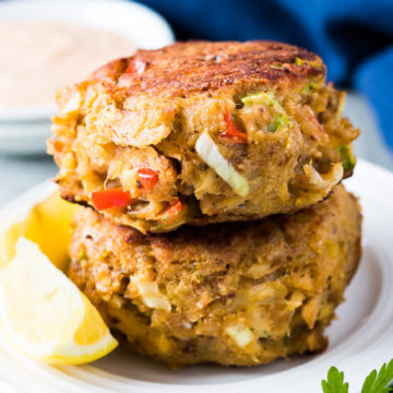 Two homemade crab cakes stacked on a plate.