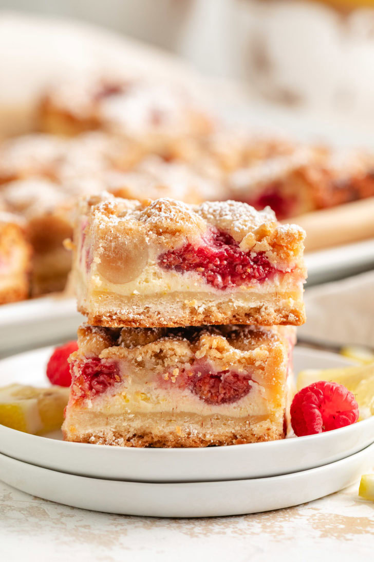 Two lemon raspberry crumble bars stacked on plates.