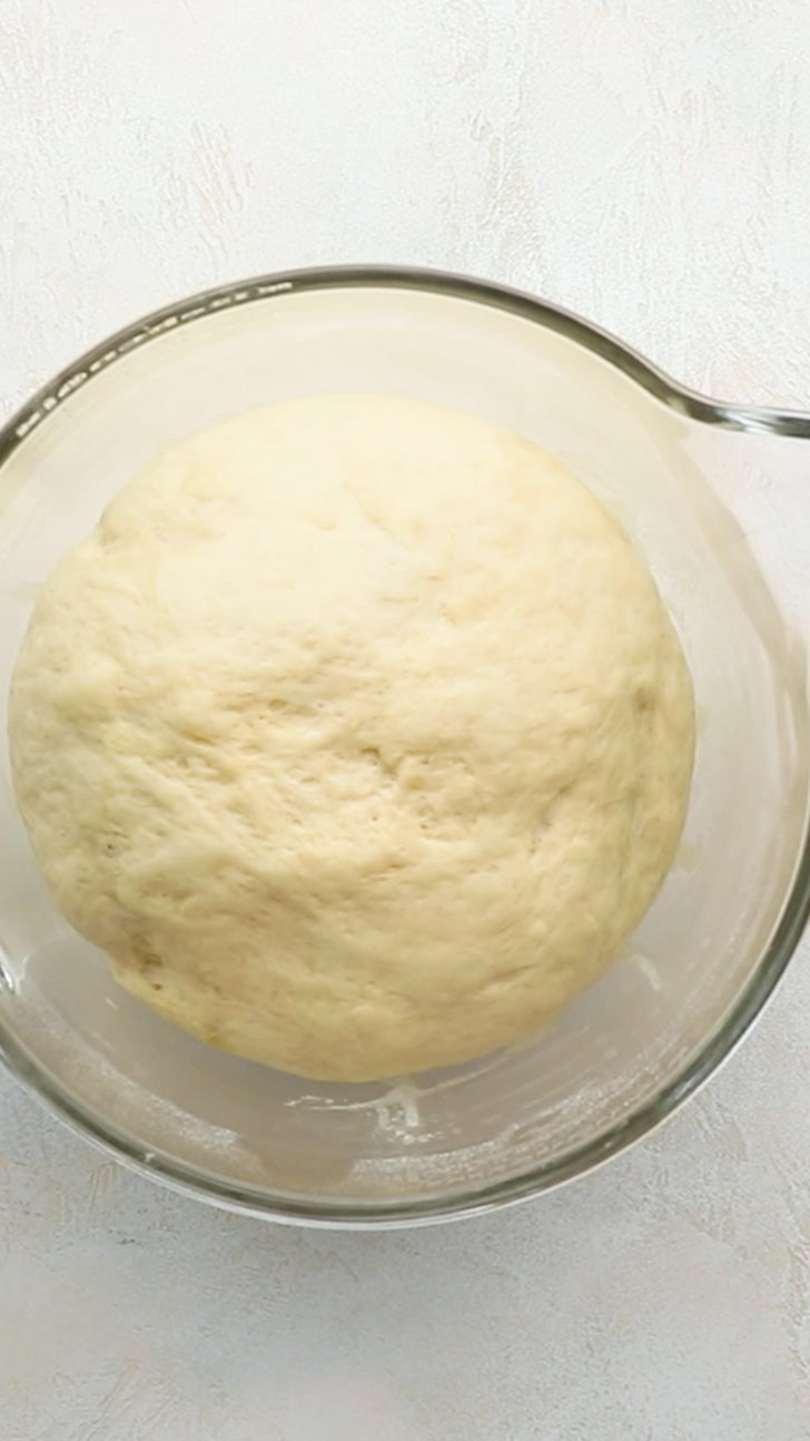 Risen lemon sweet rolls dough in glass bowl.