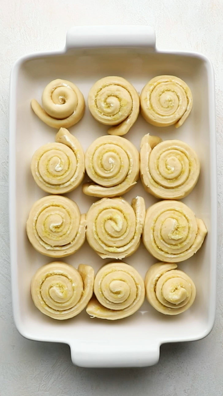 Unbaked sweet rolls arranged in white dish.