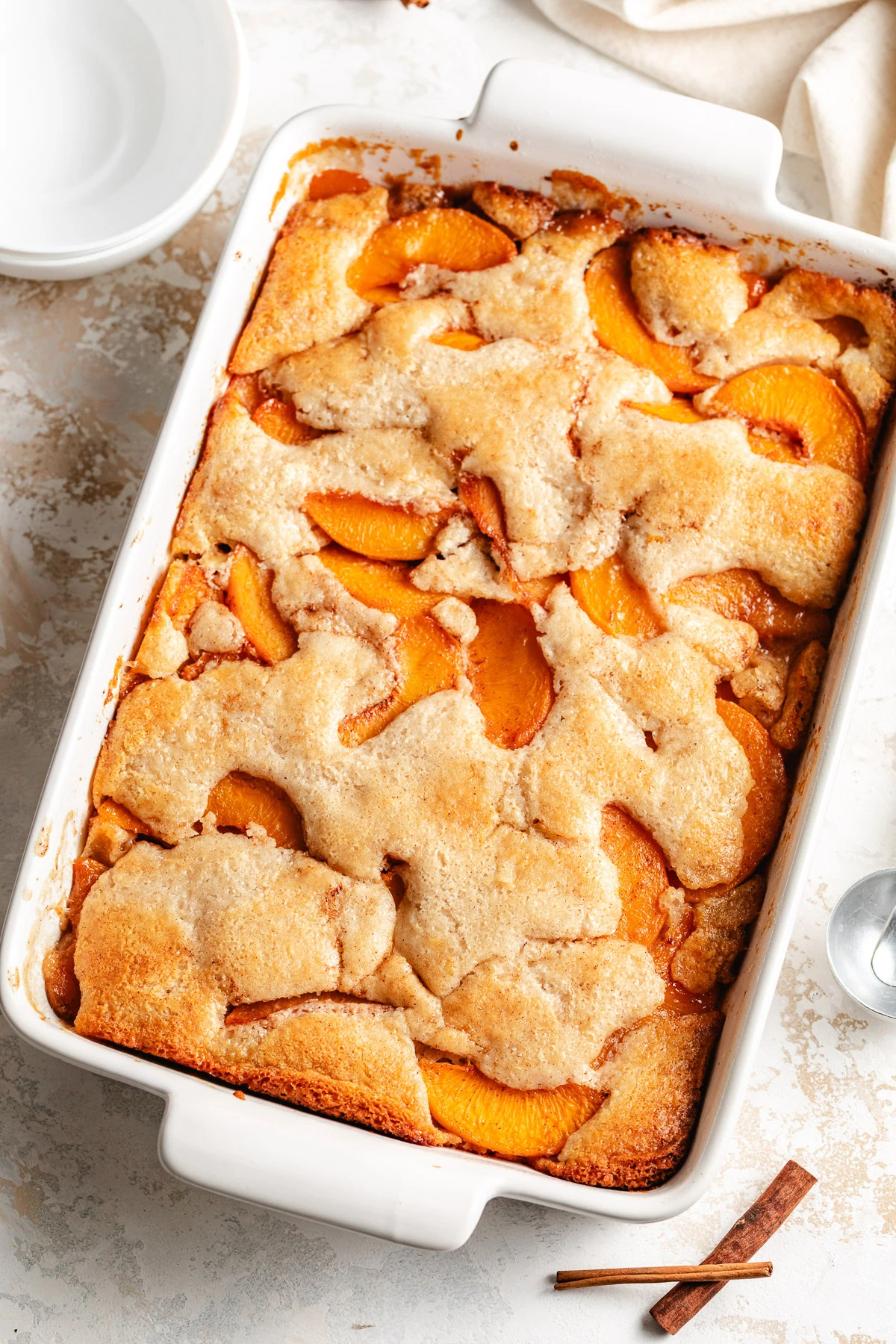 Old fashioned peach cobbler baked in a white rectangular dish.