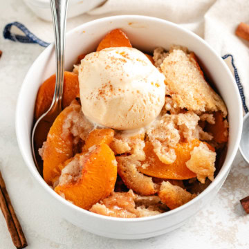 Old fashioned peach cobbler served warm with vanilla ice cream.