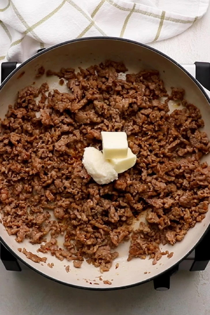 Butter and garlic added to cooked sausage.