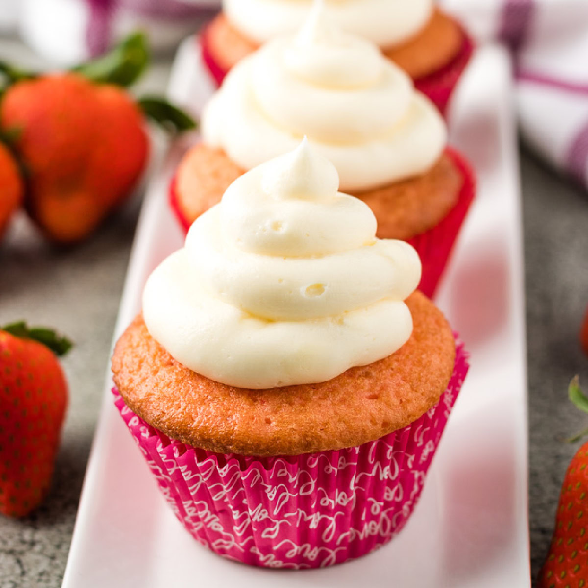 Strawberry champagne cupcakes on a white serving dish.