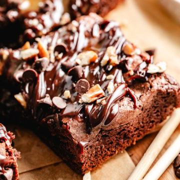 Close-up of a turtle brownie square topped with caramel, fudge, pecans, and chocolate chips.