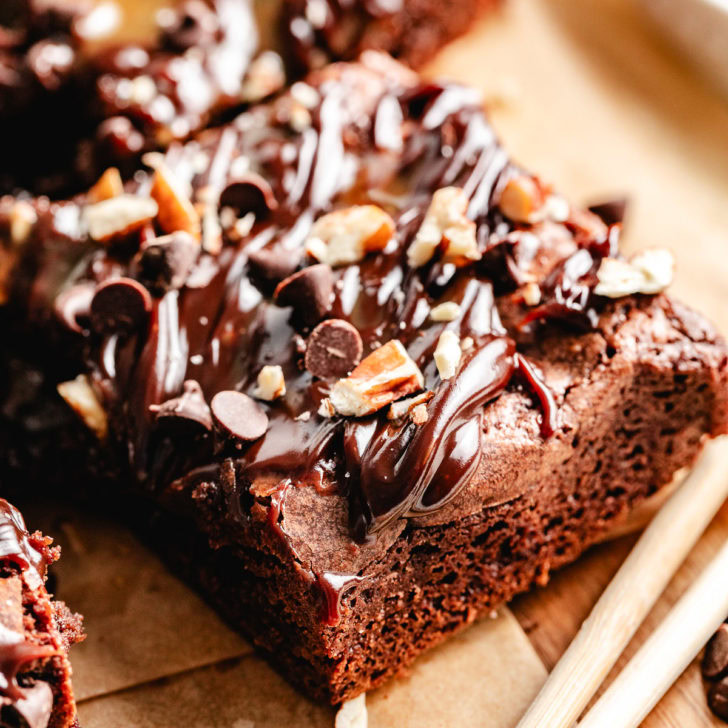 Close-up of a turtle brownie square topped with caramel, fudge, pecans, and chocolate chips.