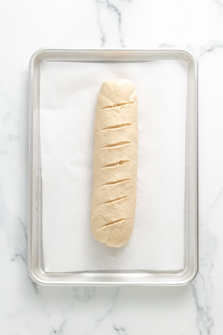 Shaped bread dough on a parchment-lined baking sheet.