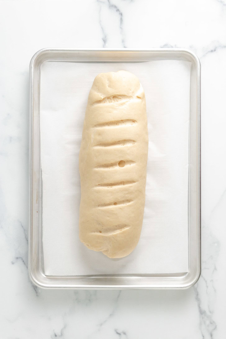 Risen bread dough with slashes on top.