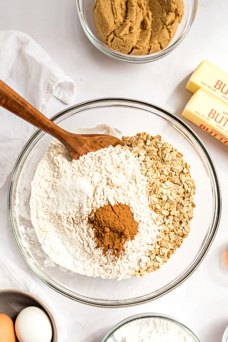 Old fashioned oats, flour, baking soda, salt, and cinnamon in a large glass mixing bowl.
