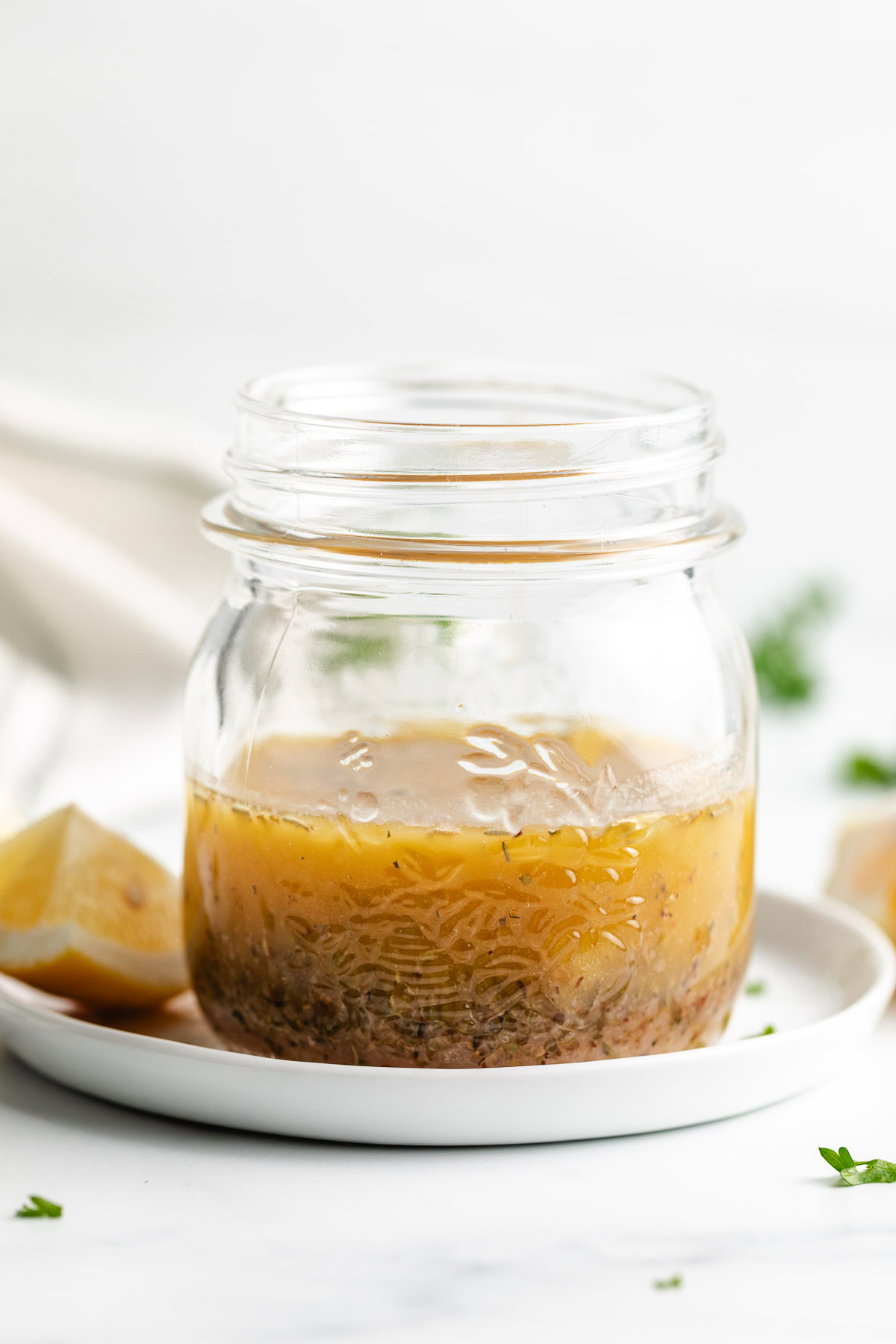 Italian dressing in a glass jar on a white plate.