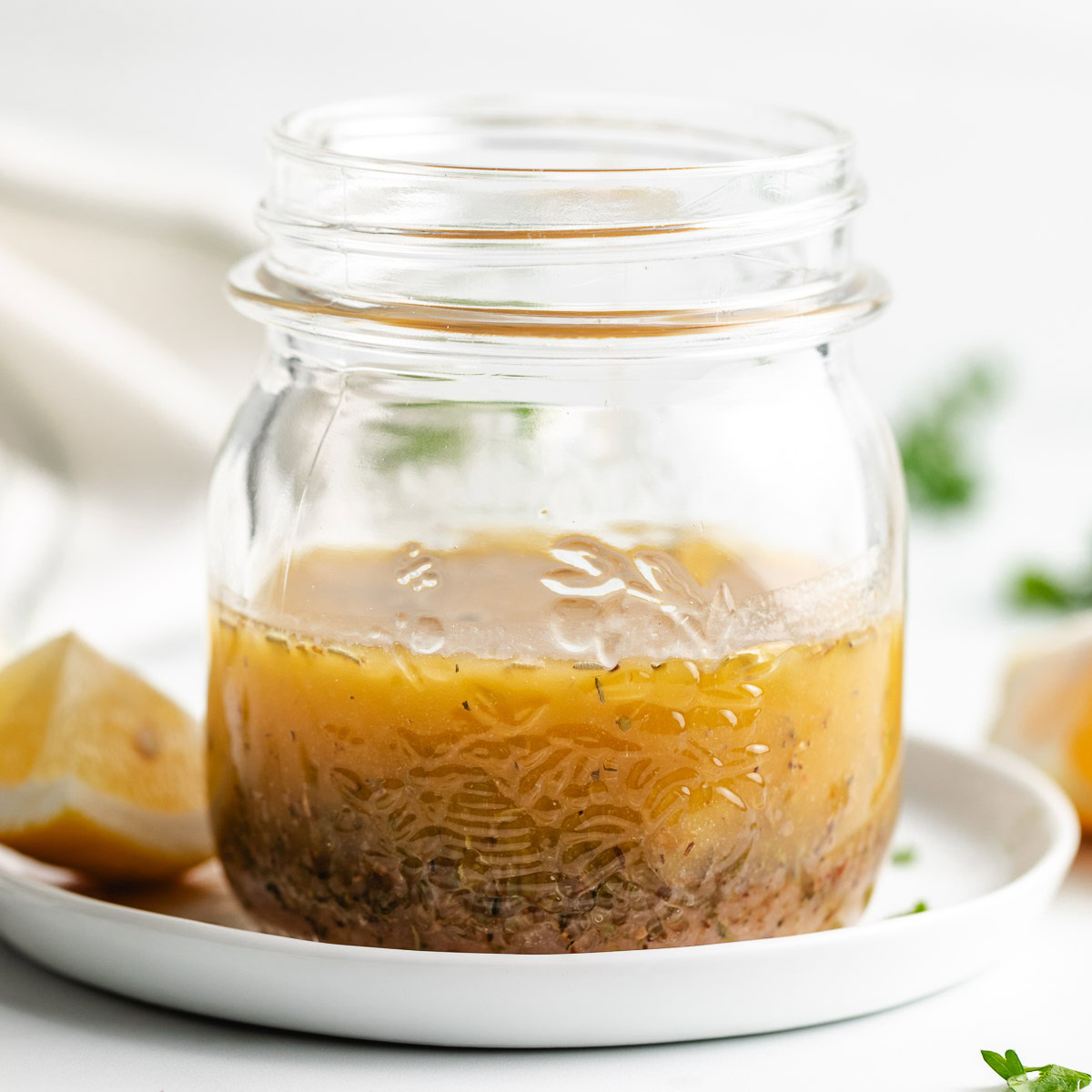 Italian dressing in a glass jar with lemon wedges.