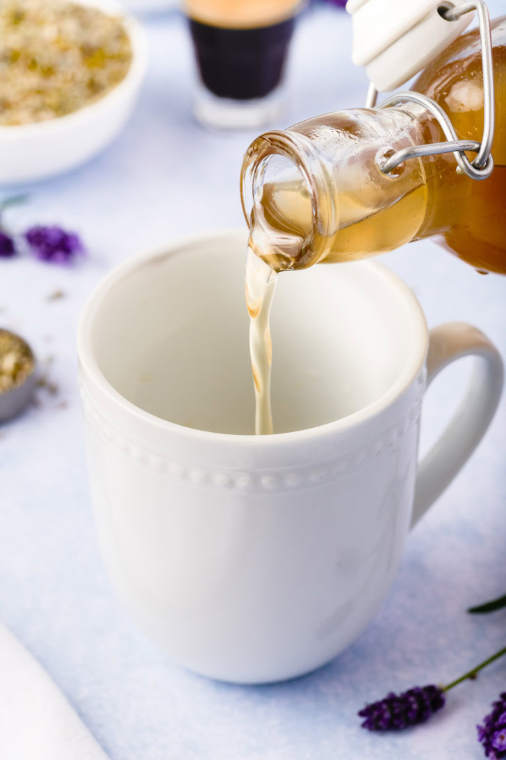 Lavender syrup being poured into a white mug.