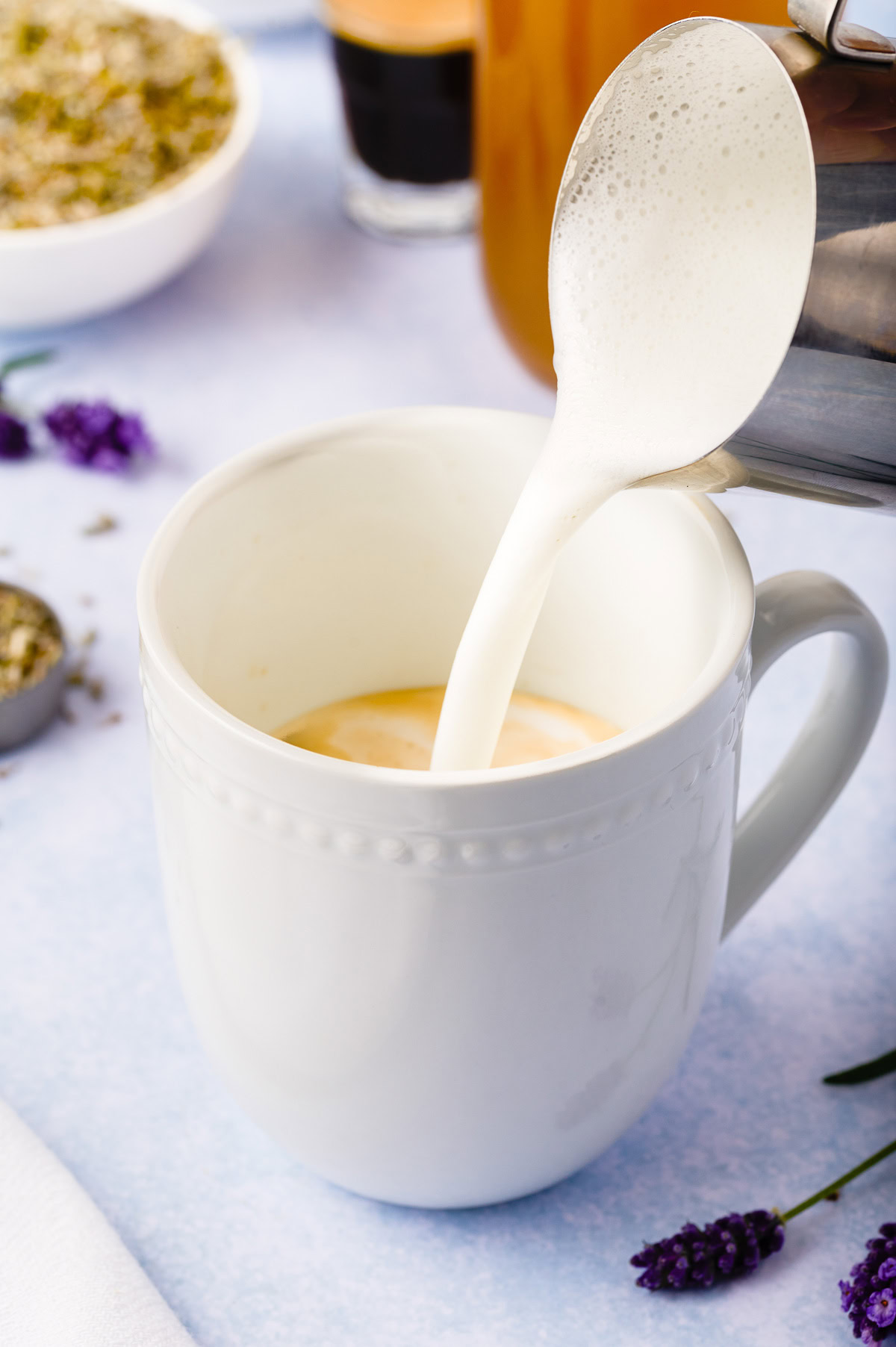 Steamed milk being poured over espresso in a white mug.
