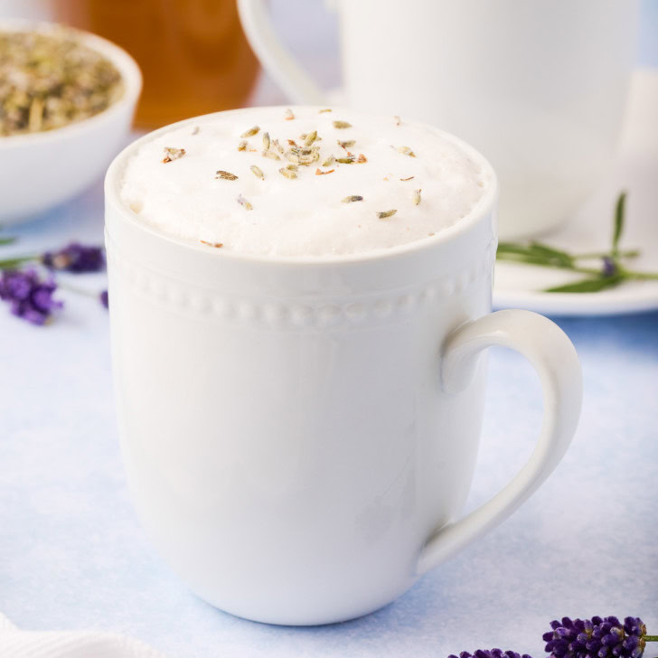 Lavender latte in a white mug with foamed milk and dried lavender.