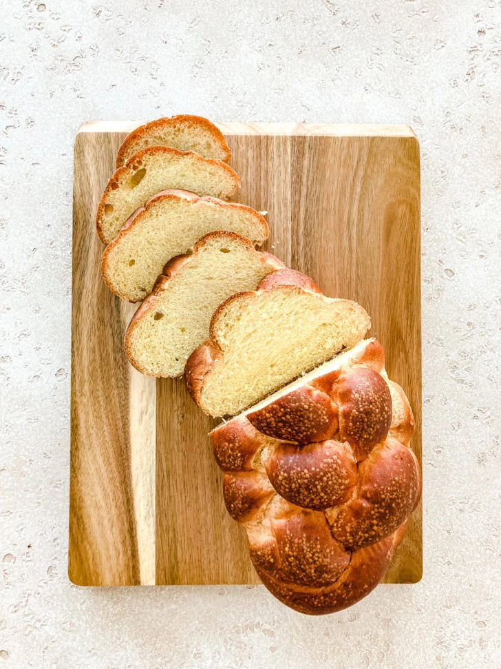 Sliced challah bread on a wooden cutting board.